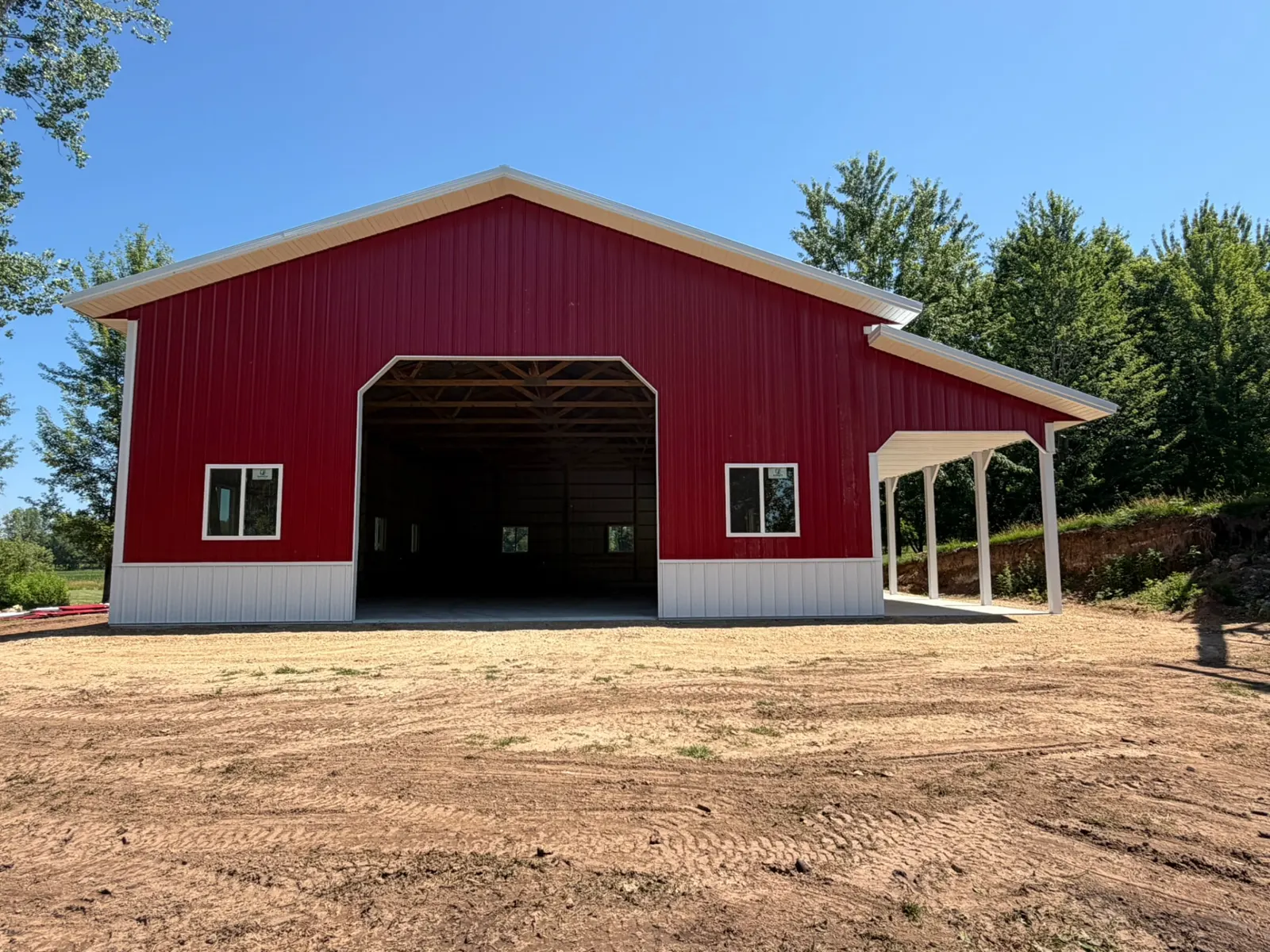 Red pole barn with white wainscot and lean-to porch, built by Kauffman Construction in Wisconsin