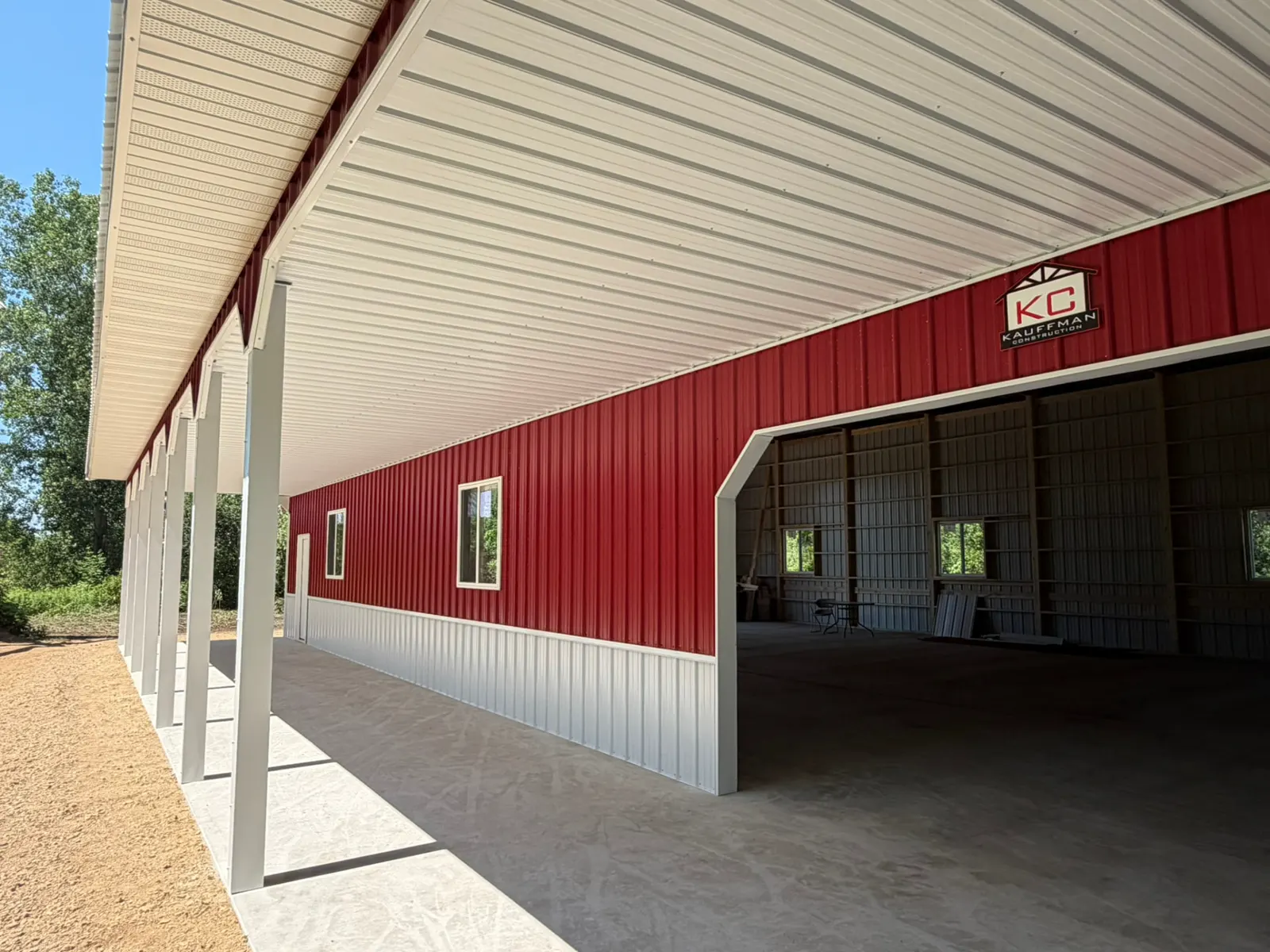 Covered porch on red pole barn with Kauffman Construction sign, built by Kauffman Construction in Wisconsin