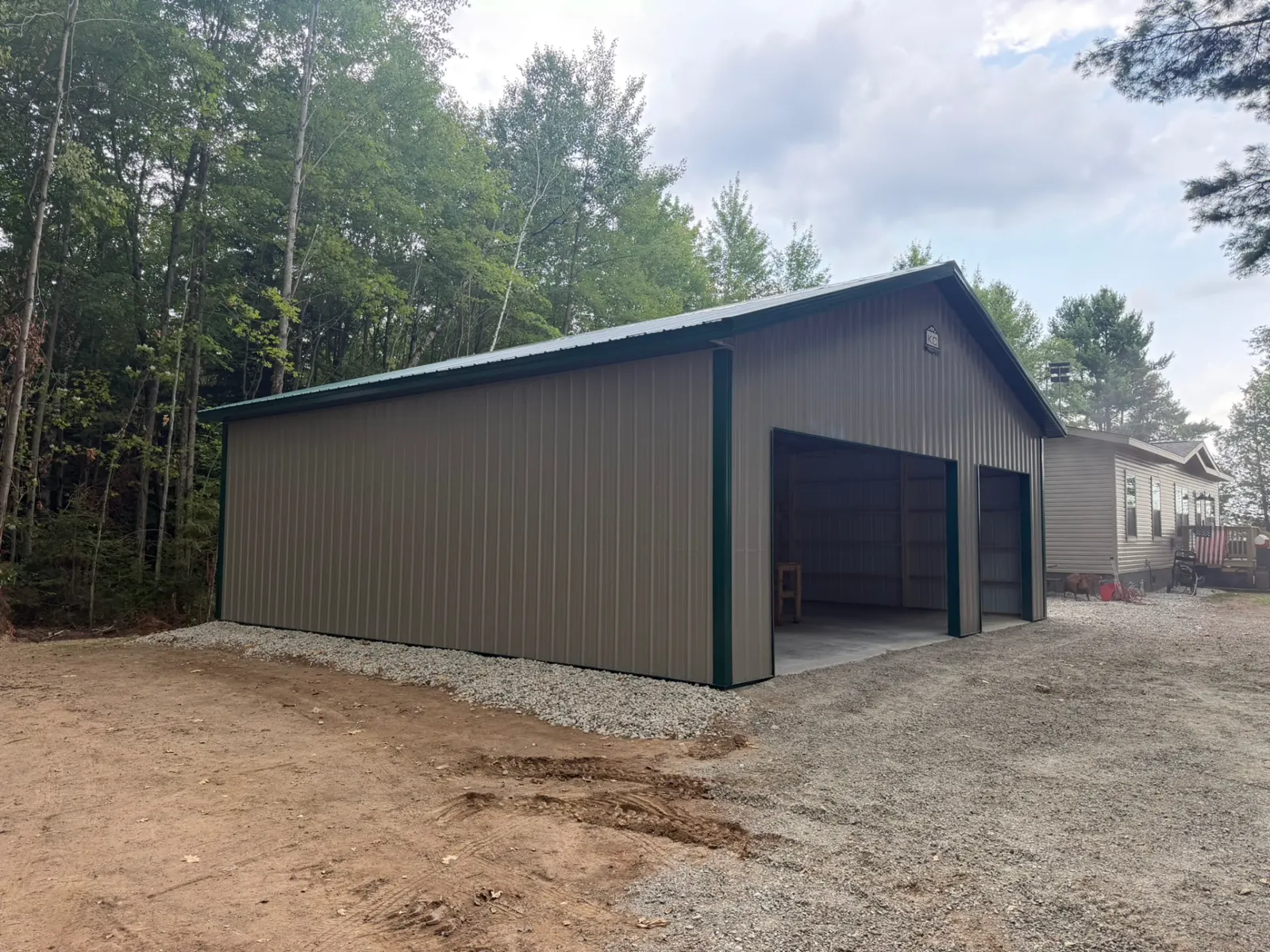 Two-car pole garage with green trim on gravel drive, built by Kauffman Construction in Wisconsin