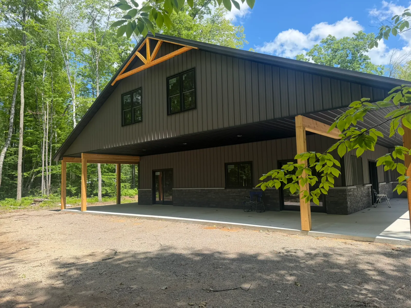 Barndominium with timber truss gable and covered concrete porch, built by Kauffman Construction in Wisconsin