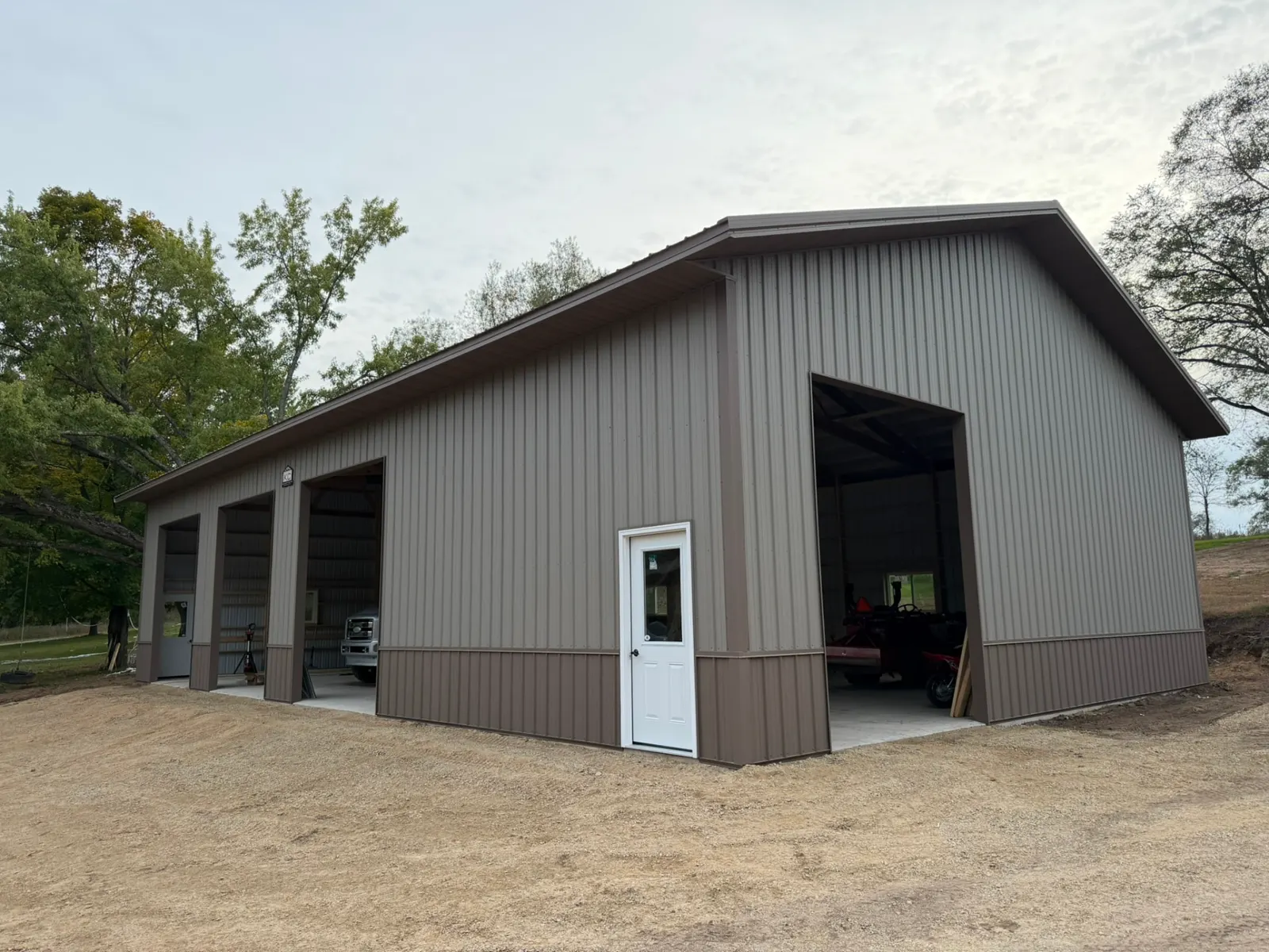 Pole shed with four overhead doors and brown wainscot, built by Kauffman Construction in Wisconsin